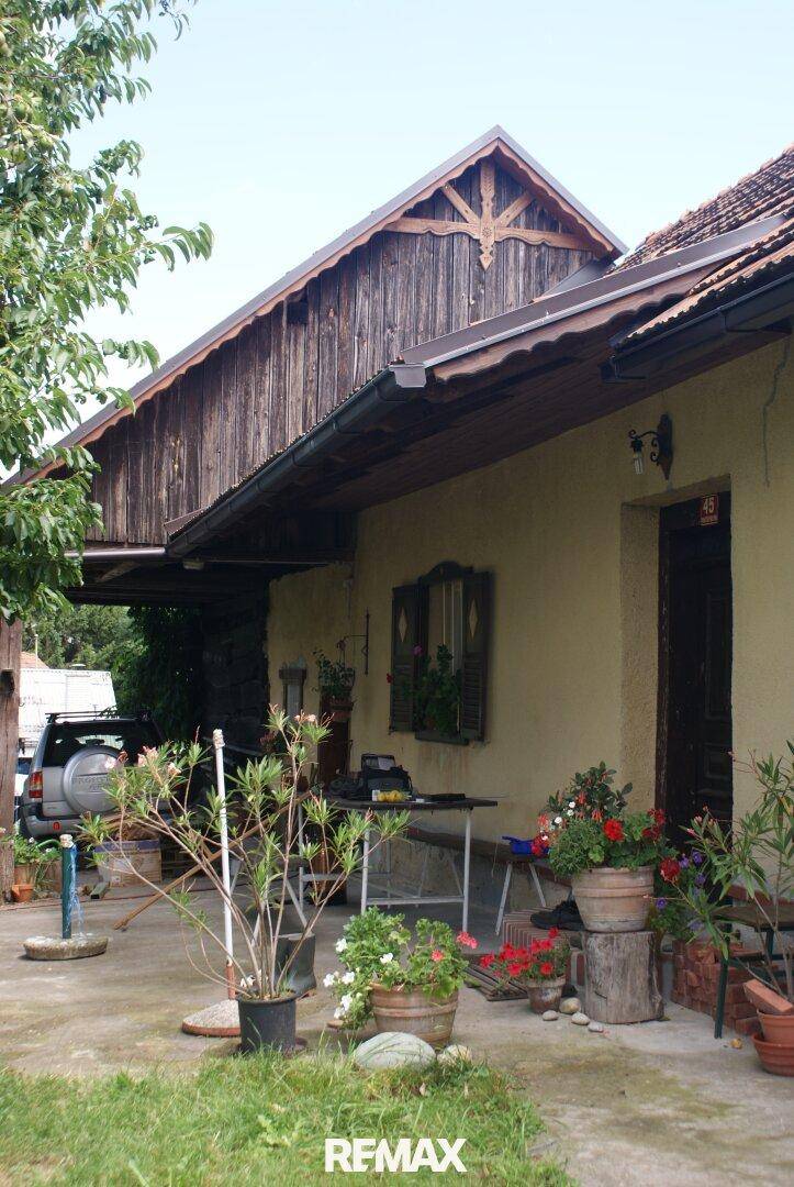 Rustikales Haus mit überdachtem Eingangsbereich und einer kleinen Terrasse mit Pflanzen.