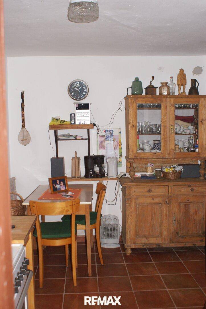Traditionelle Küche mit Holztisch, Stühlen und einem antiken Holzschrank.