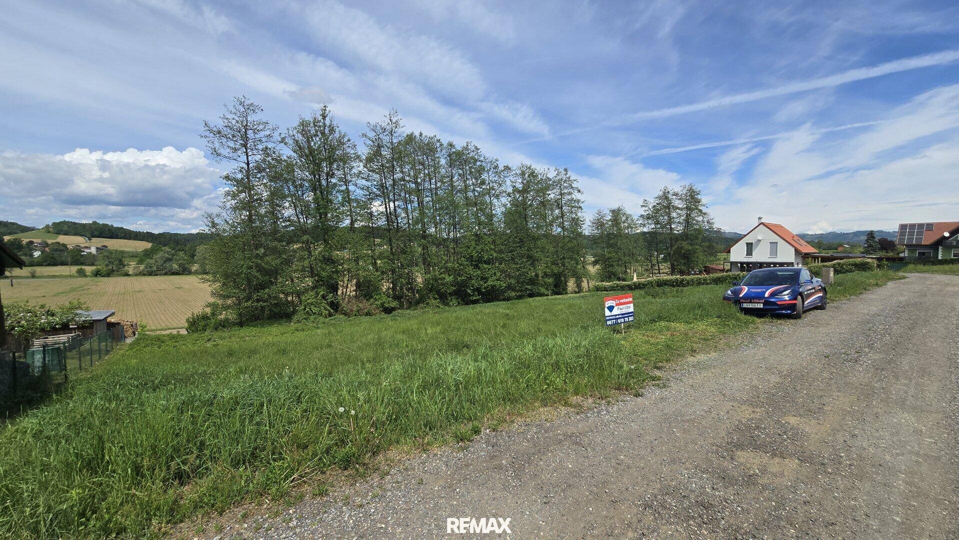 Weitläufiges Baugrundstück mit Schotterweg und Panoramablick auf die Landschaft.