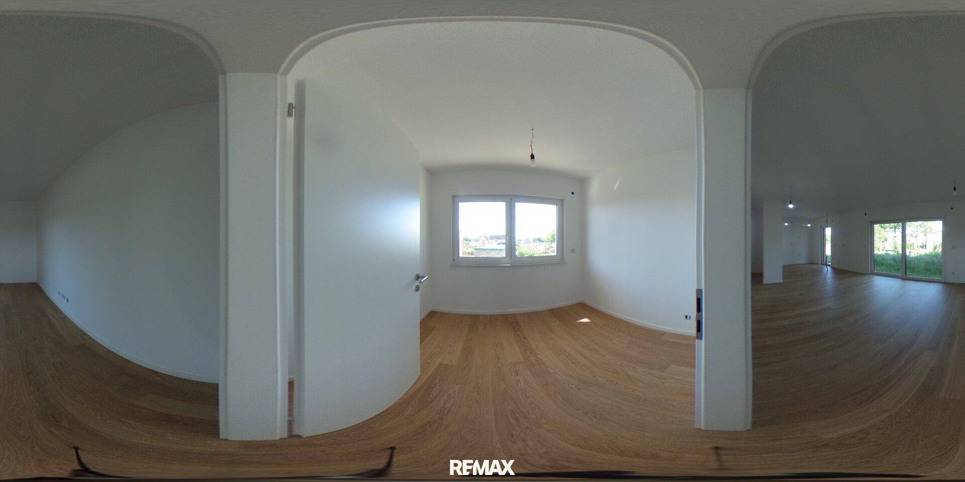 Helles Schlafzimmer mit Parkettboden und Fenster, das viel Tageslicht hereinlässt.