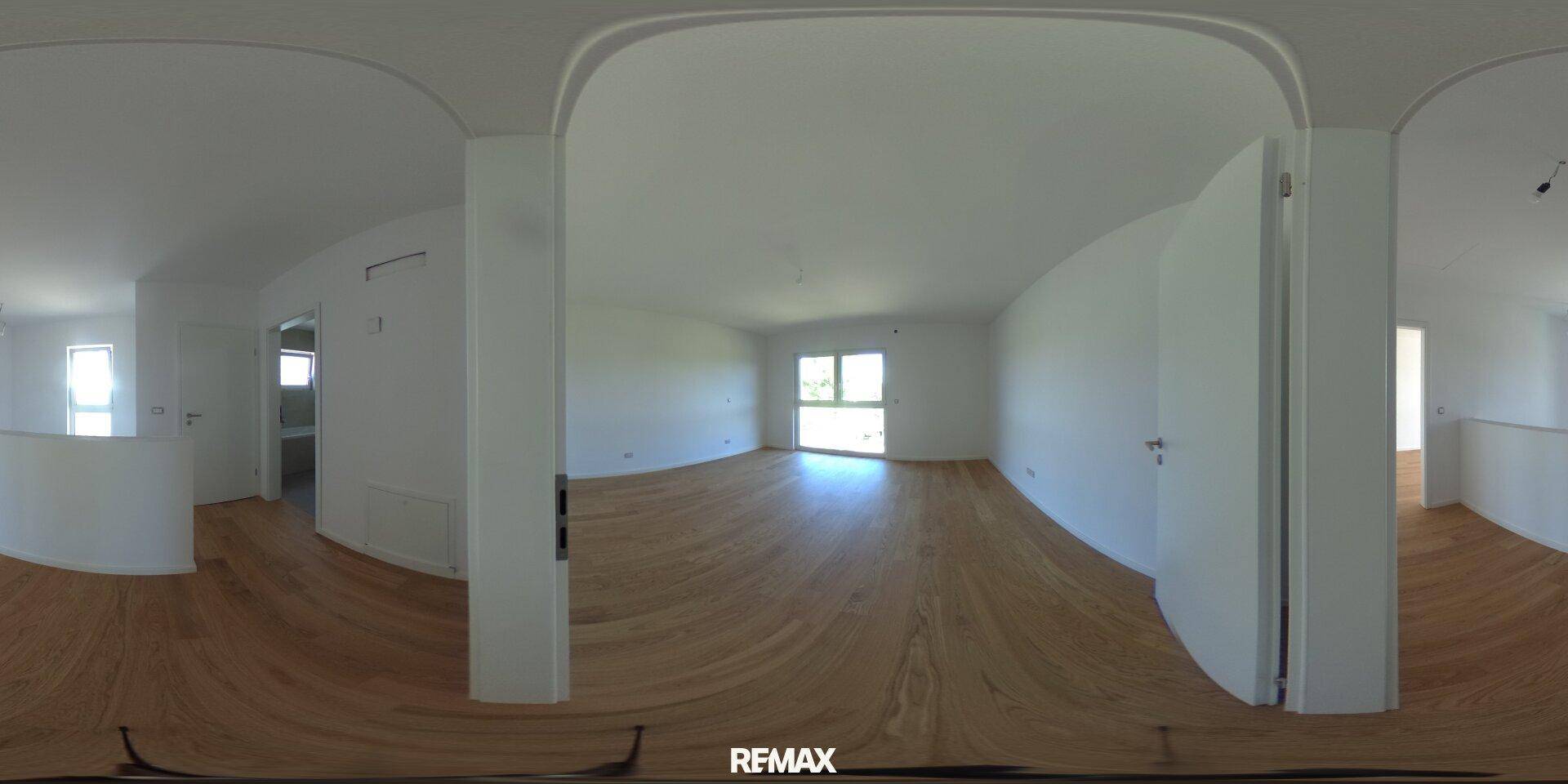Offener Wohnbereich mit Parkettboden und Zugang zu einem weiteren Zimmer, sehr hell.