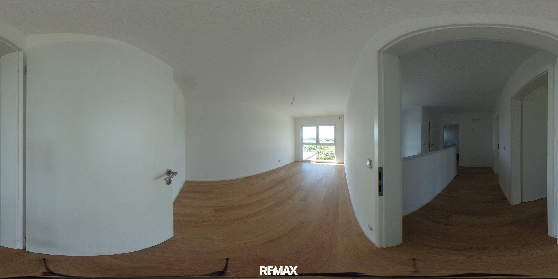 Heller Wohnbereich mit Parkettboden und Blick ins Freie durch große Fenster.