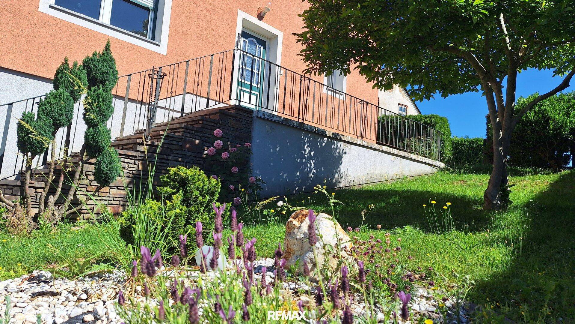 Detailansicht des Gartens mit Lavendel und Steinen vor der Hausfassade und Treppe.