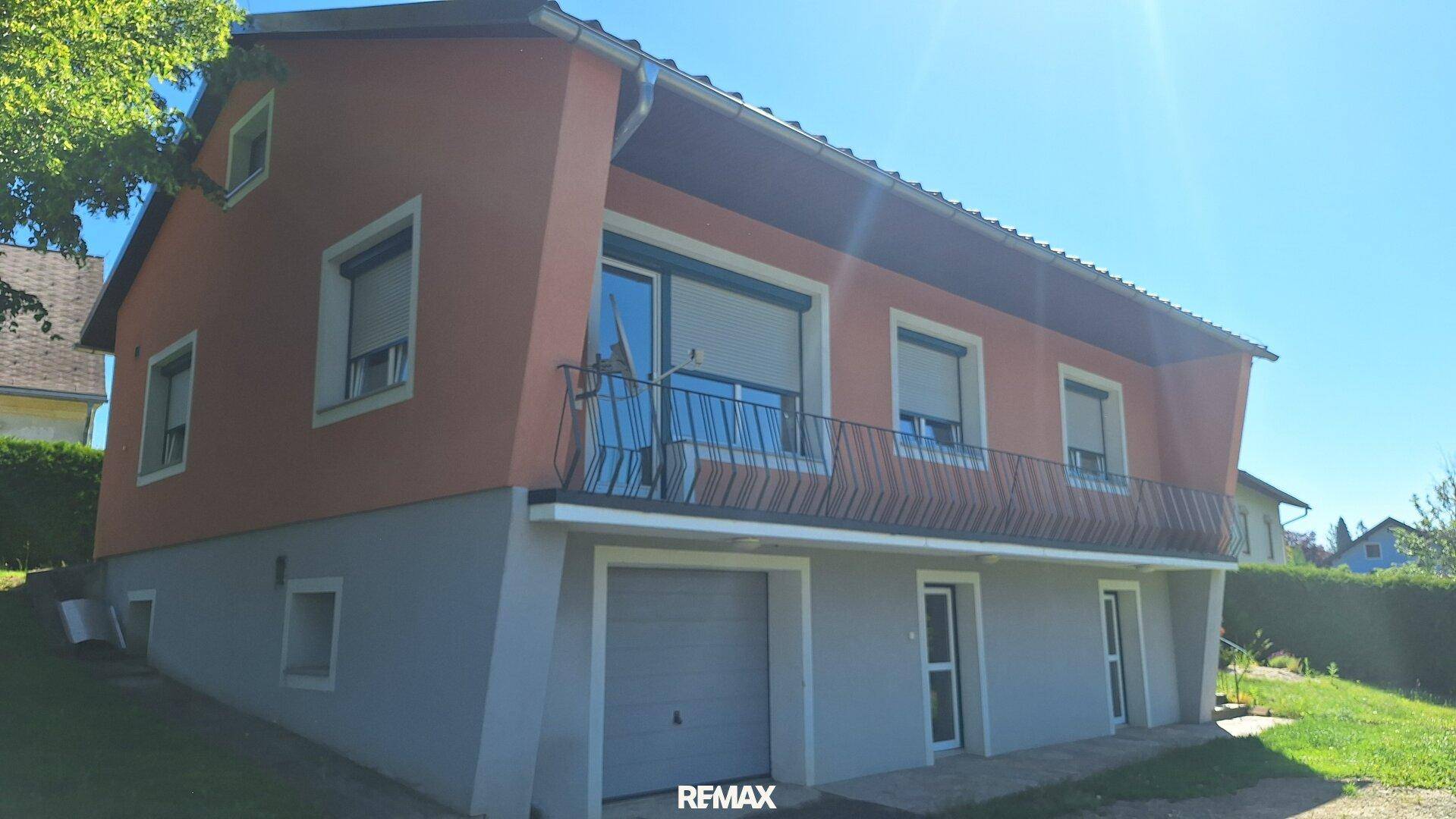 Seitenansicht des Hauses mit Garage im Untergeschoss und Balkon im Obergeschoss.