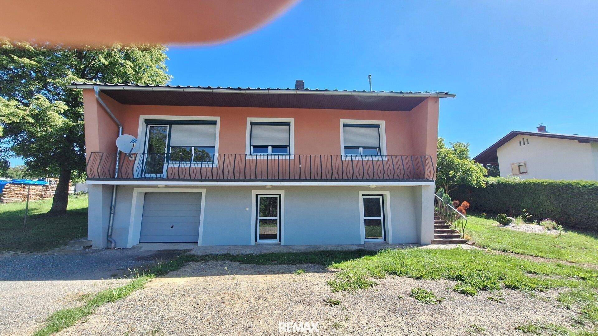 Vorderansicht des Einfamilienhauses mit Garage, Balkon und Zugang über eine Außentreppe.