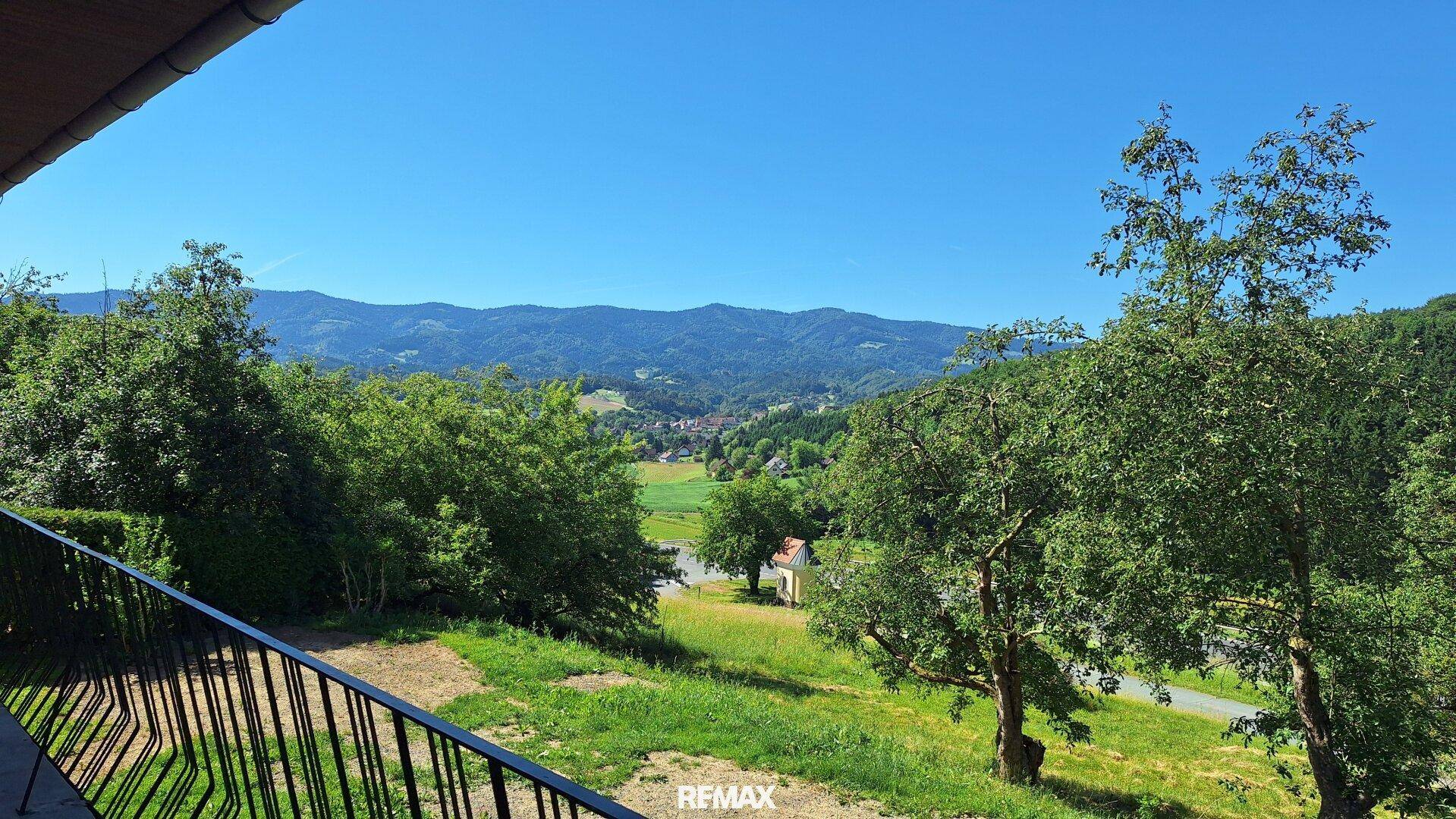 Weitläufiger Blick vom Balkon über grüne Hügel, Wälder und ein malerisches Tal.