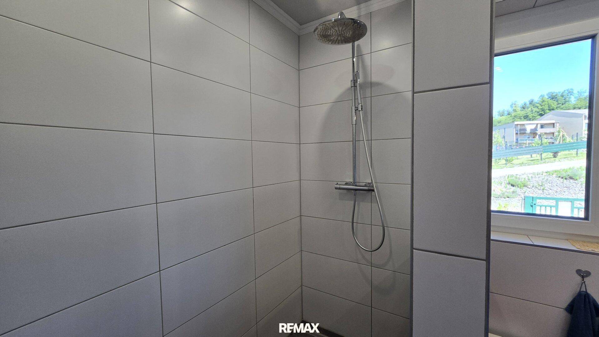 Geräumige Duschkabine mit modernen Fliesen und Regendusche im Badezimmer.