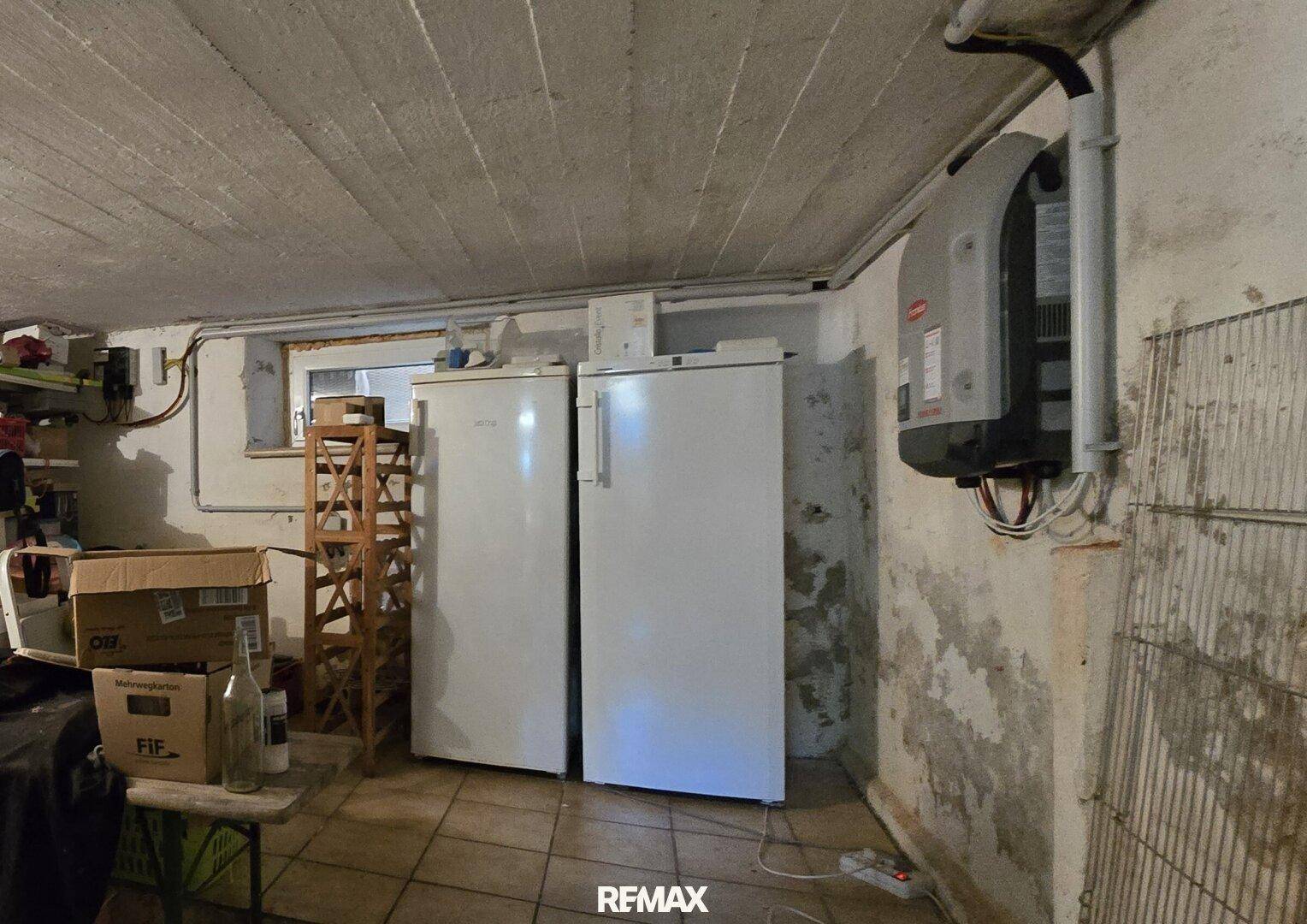 Kellerraum mit zwei Kühlschränken, Fliesenboden und sichtbaren Installationen.