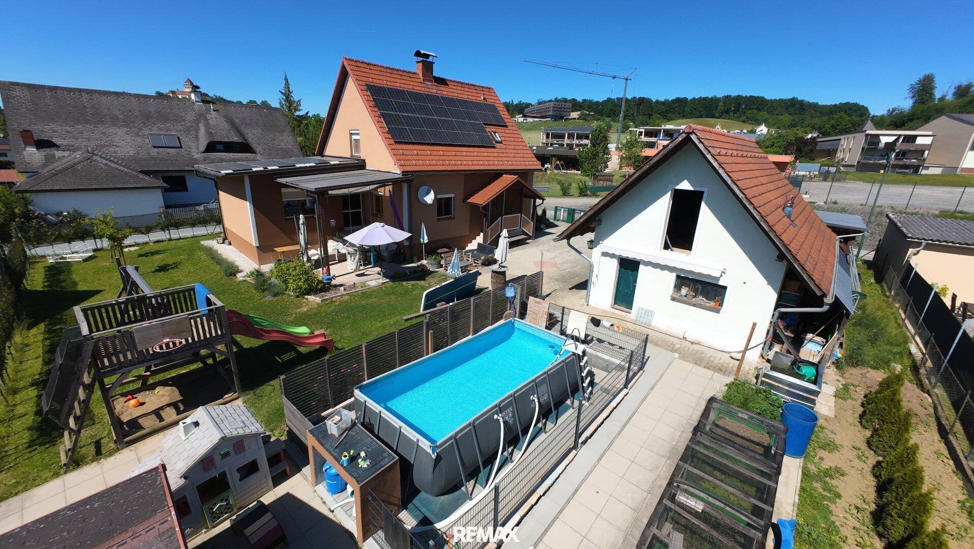 Luftaufnahme des Gartens mit einem Aufstellpool, Kinderspielplatz und weiteren Nebengebäuden.