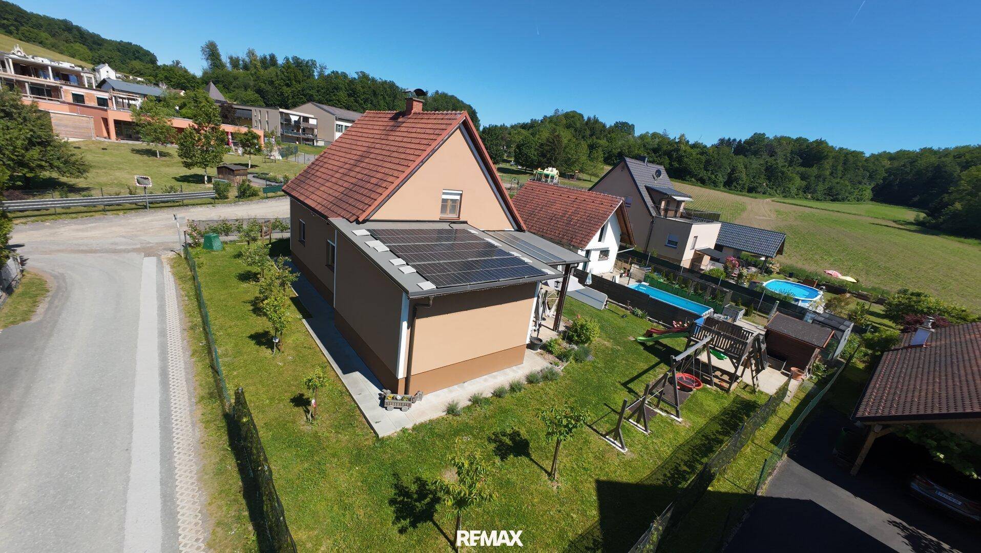 Luftaufnahme des Einfamilienhauses mit Solaranlage, Garten und Blick auf die hügelige Landschaft.