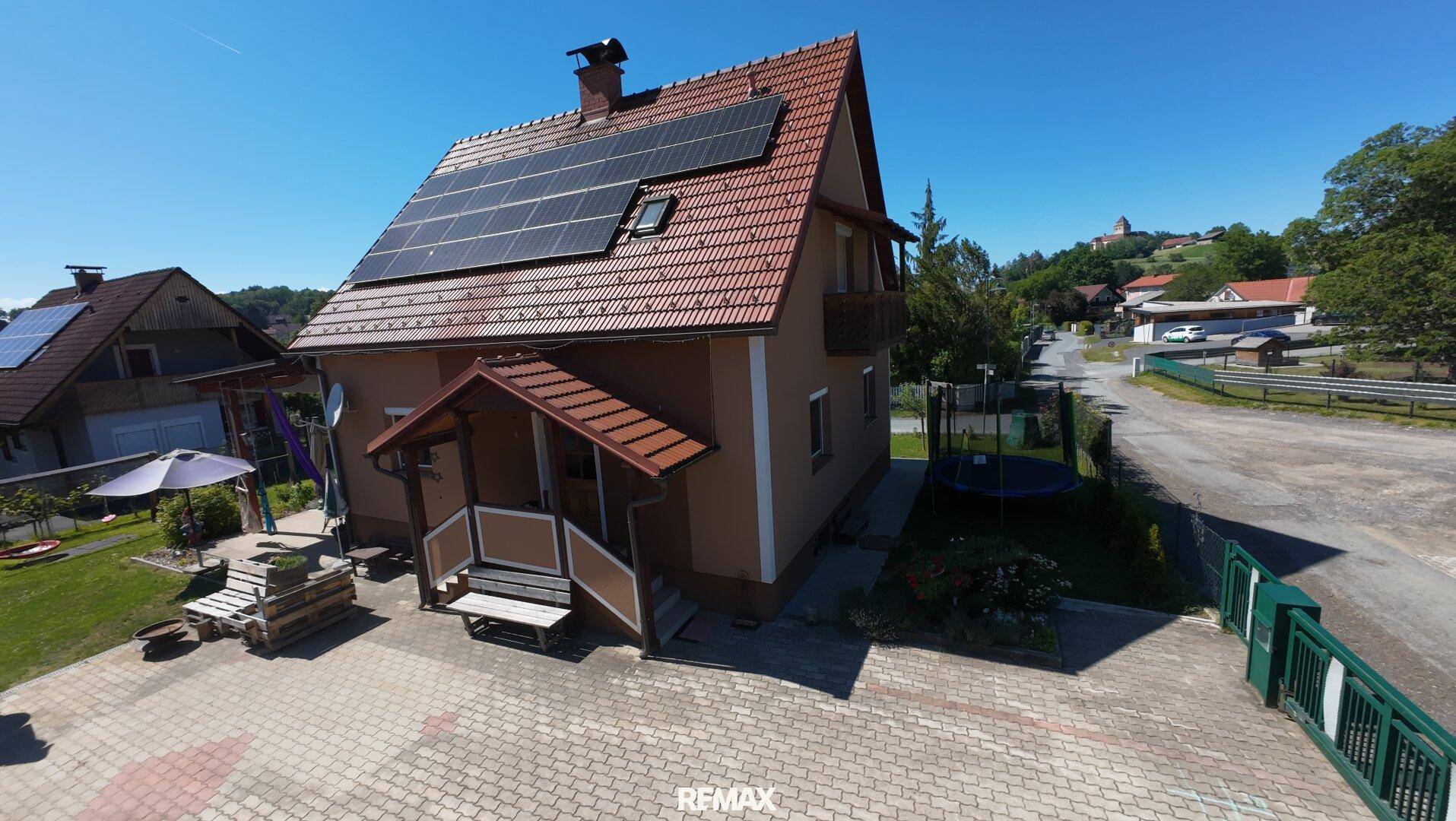 Einfamilienhaus mit Solaranlage auf dem Ziegeldach, gepflastertem Vorplatz und kleinem Balkon.