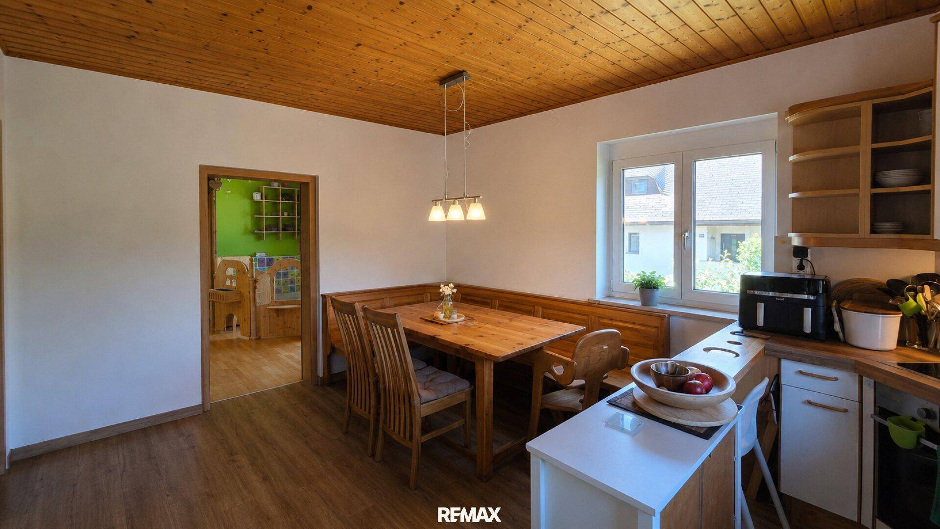 Gemütliche Wohnküche mit Holztisch, Eckbank und Holzdecke, ideal für gemeinsame Mahlzeiten.