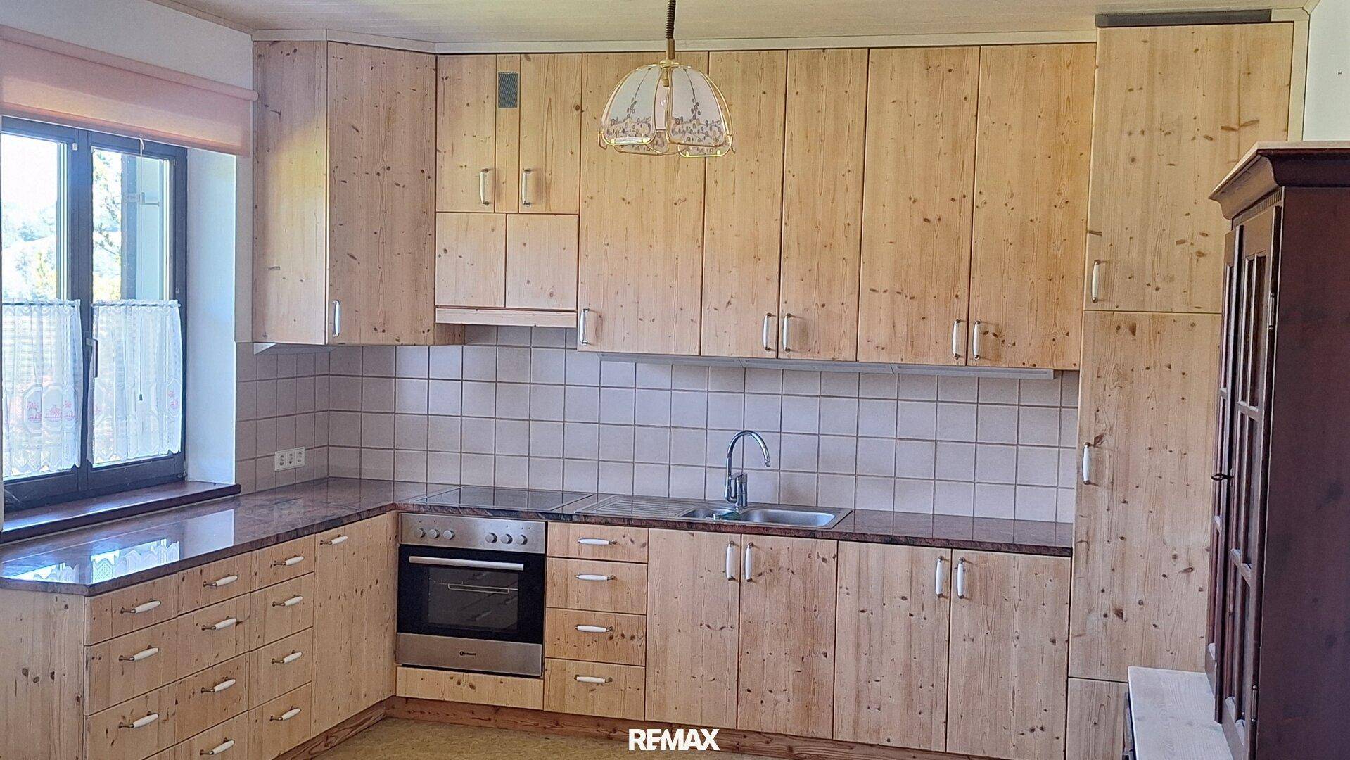Traditionelle Küche mit Holzschränken, Einbaugeräten und Fliesenrückwand, funktional und hell.
