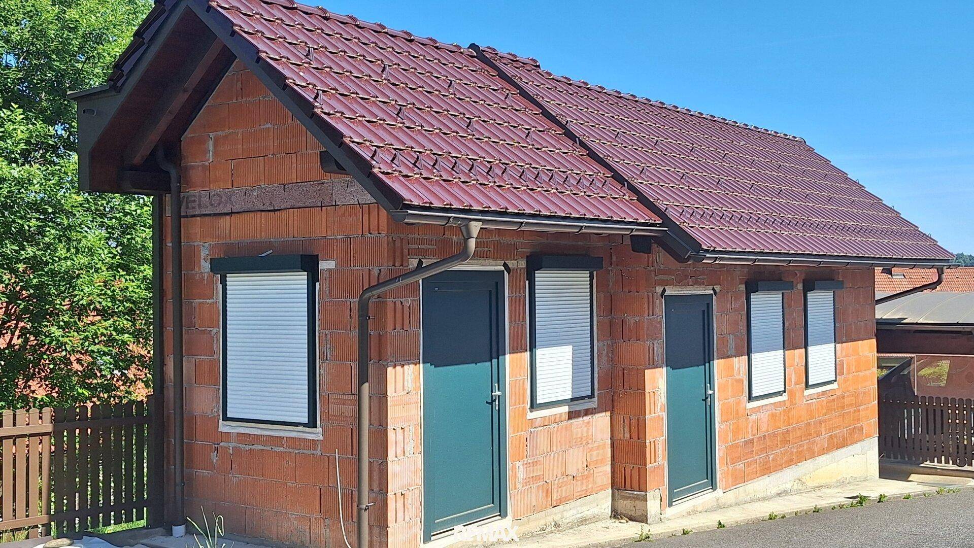 Kleines Nebengebäude aus Ziegeln mit Rollläden und Satteldach, in massiver Bauweise errichtet.