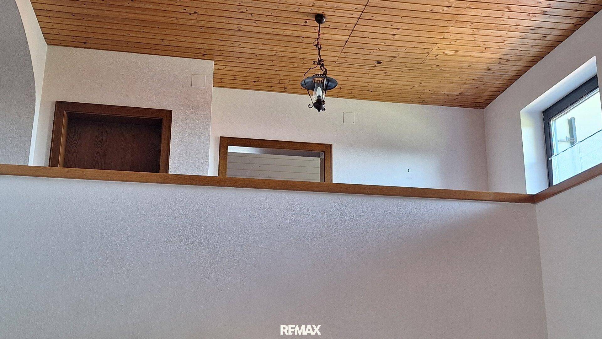 Raum mit Holzdecke, traditioneller Hängelampe und Holztüren, einladend und hell.