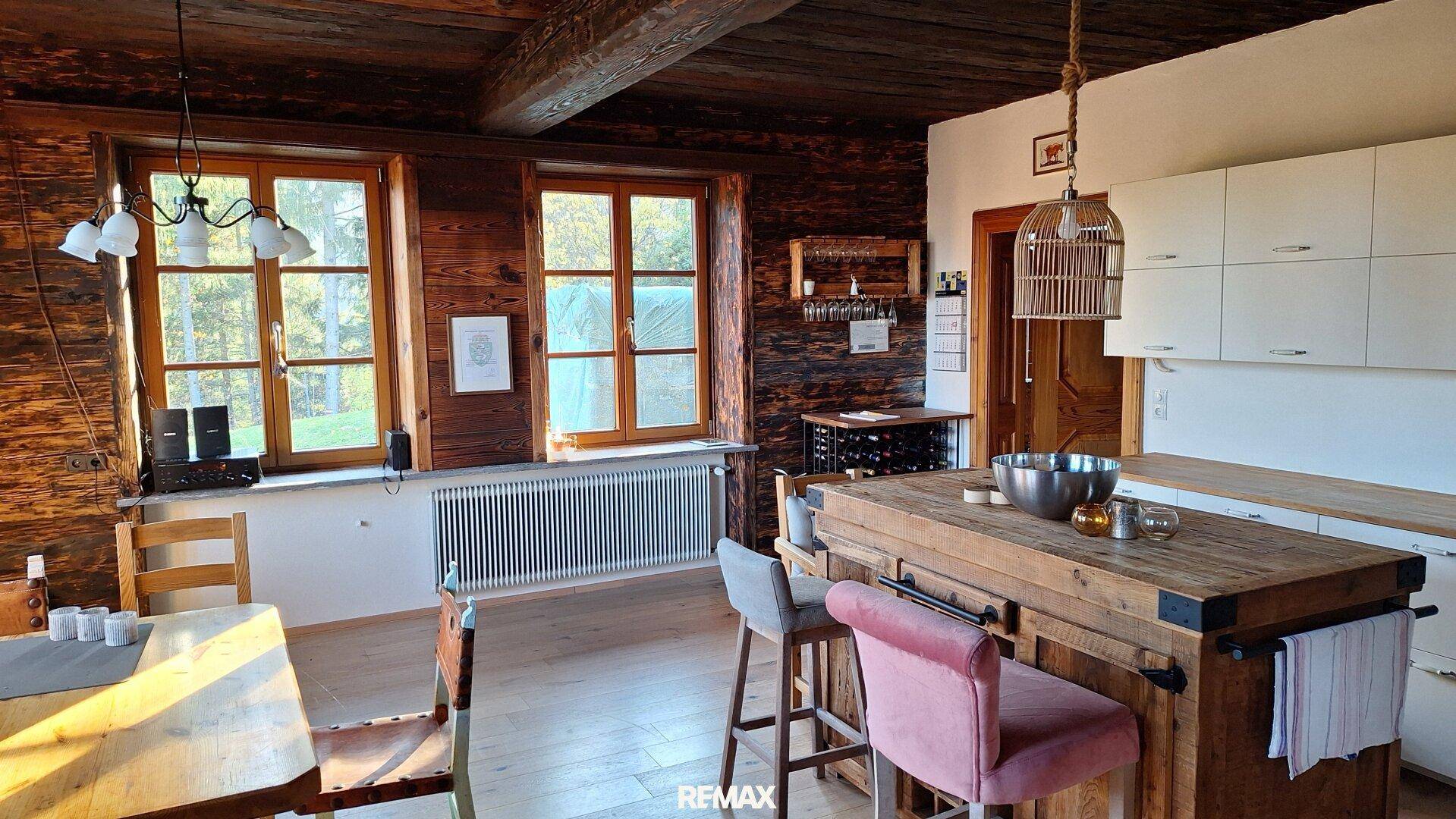 Gemütliche Küche mit Holzwänden, Holzbalkendecke und einer rustikalen Kücheninsel mit Barhockern.