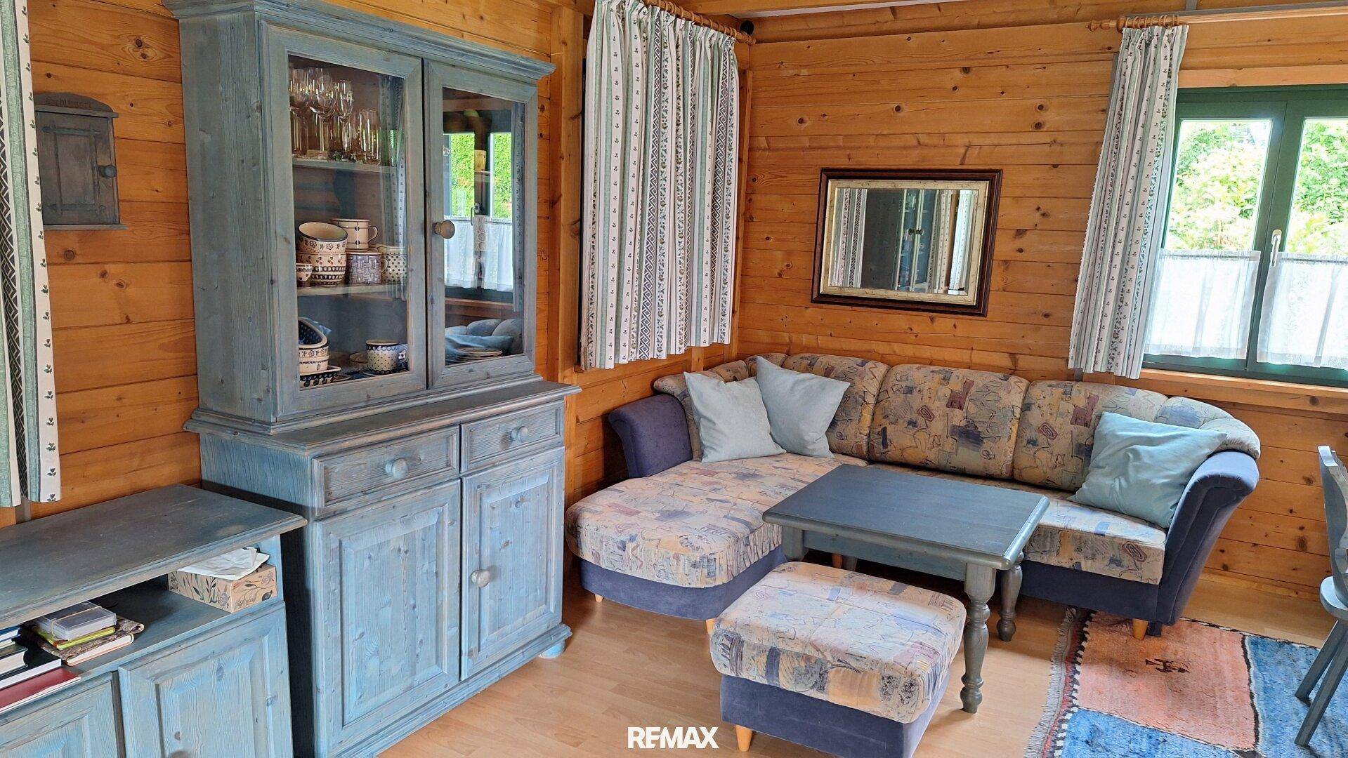 Gemütliches Wohnzimmer mit Holzwänden, bequemer Couch und traditionellem Holzschrank.