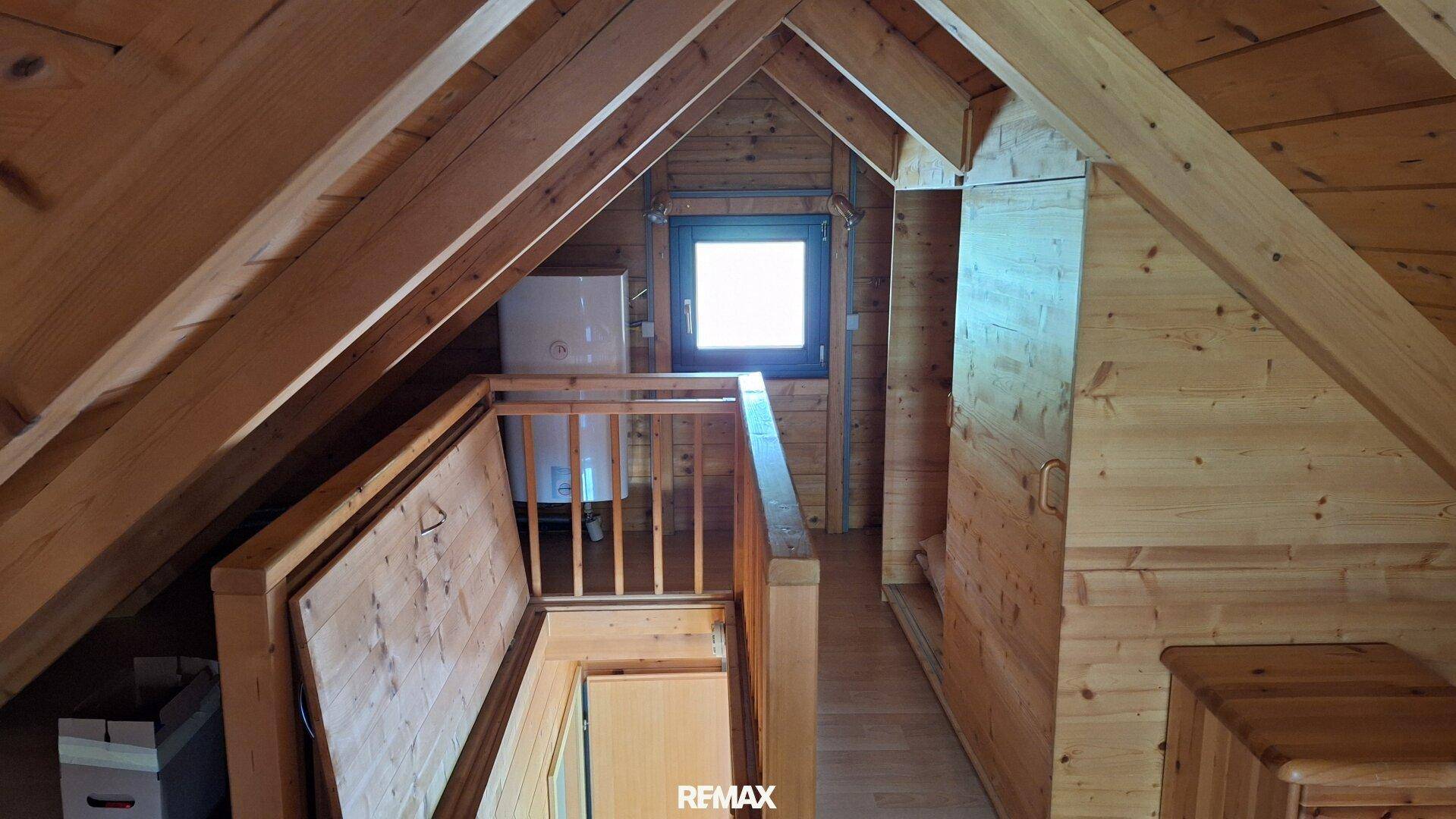 Dachgeschoss mit sichtbaren Holzbalken und kleinem Fenster, bietet zusätzlichen Stauraum.