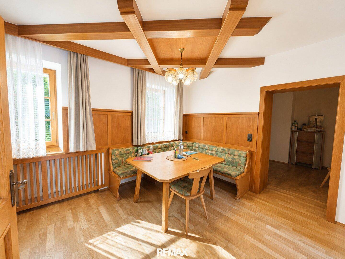 Gemütliches Esszimmer mit traditioneller Holzvertäfelung, sichtbaren Deckenbalken und Eckbank.
