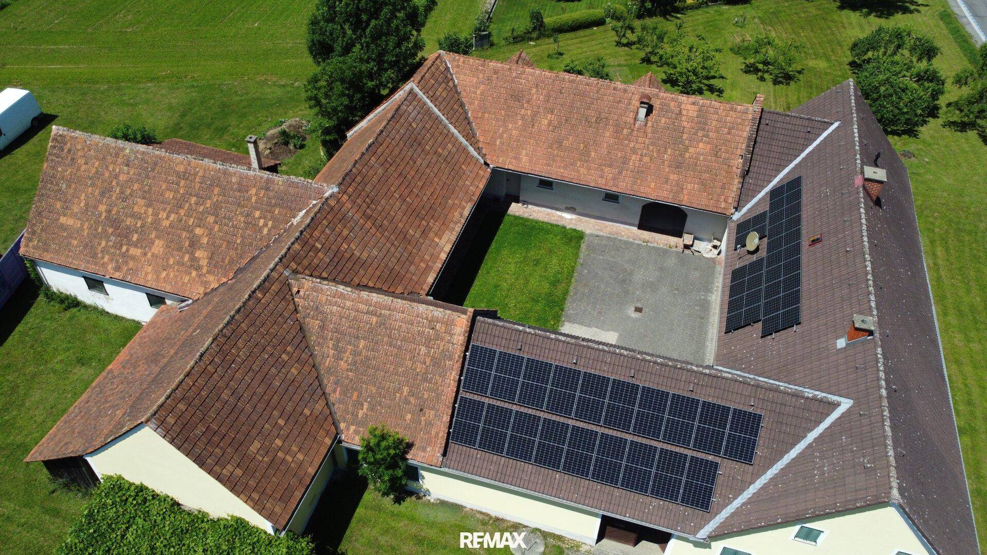 Weitläufiger Gebäudekomplex aus der Vogelperspektive mit Innenhof und Solaranlage auf dem Ziegeldach.
