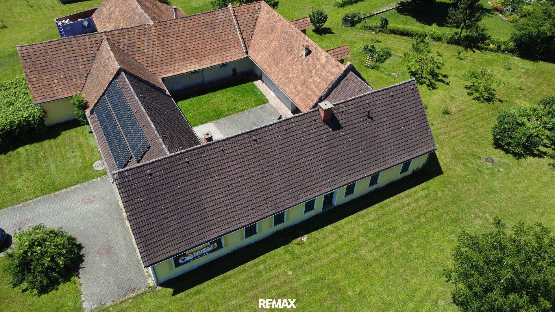 Überblick über den ländlichen Gebäudekomplex mit großem Innenhof und Solarmodulen auf einem der Dächer.