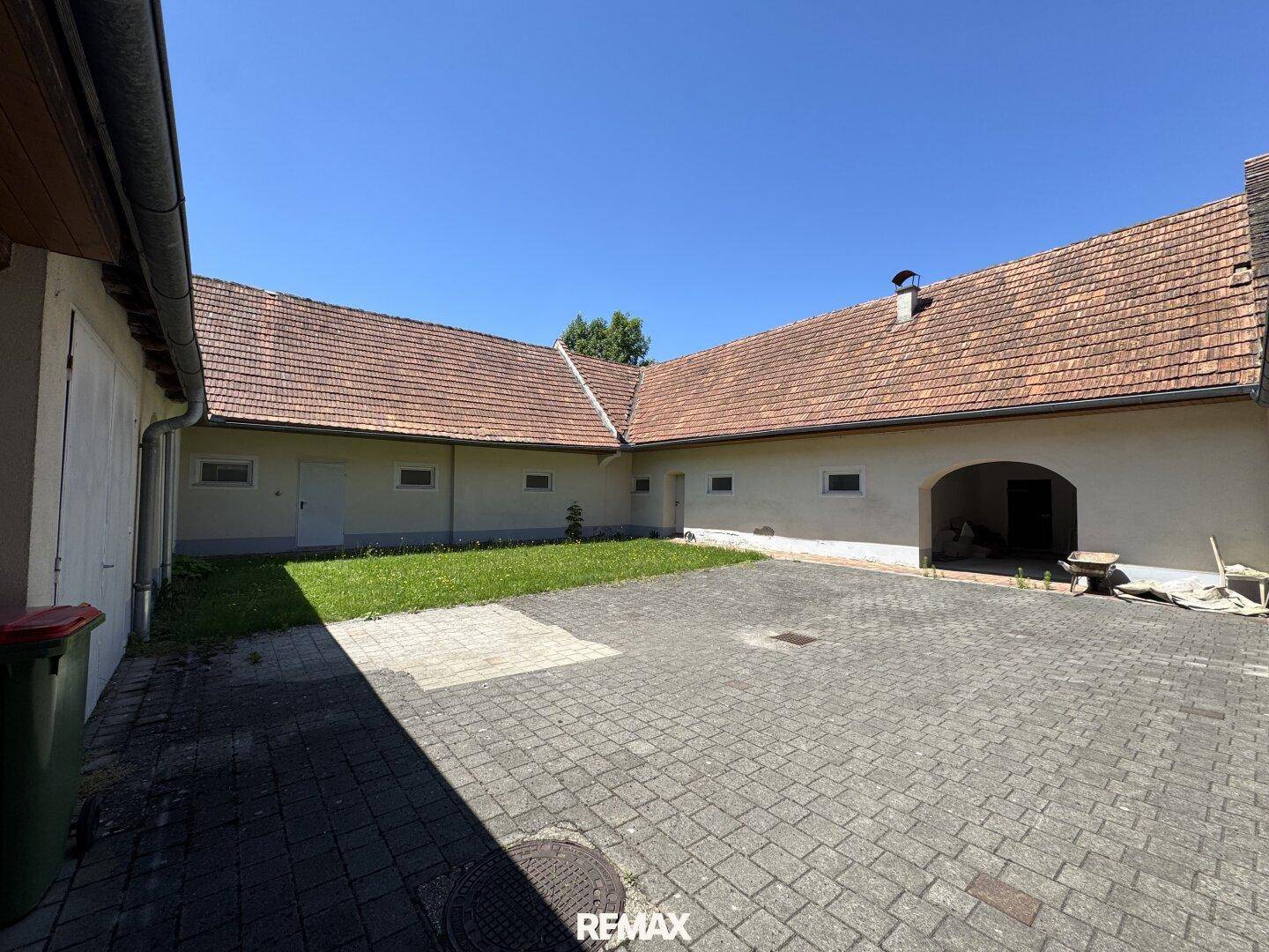Gepflasterter Innenhof mit Rasenfläche, umgeben von den Gebäudeteilen unter blauem Himmel.