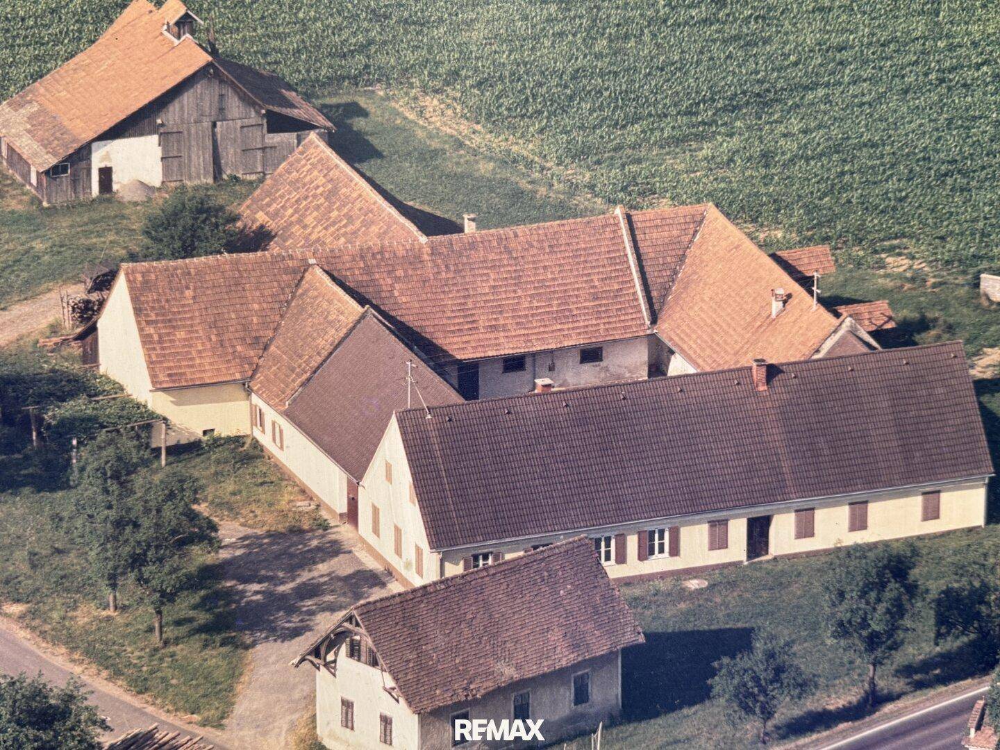 Historische Luftaufnahme des weitläufigen Gebäudekomplexes mit ländlicher Umgebung und älterer Bausubstanz.