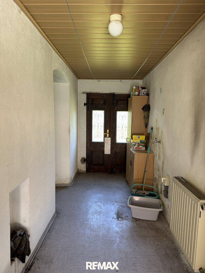 Eingangsbereich mit Holztür, Holzdecke und einem Heizkörper, der auf den Flur führt.