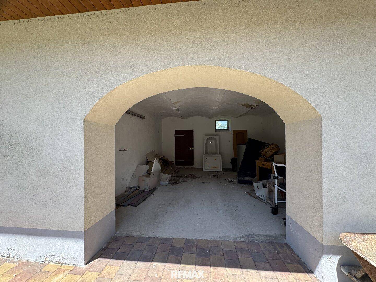 Blick durch einen großen Torbogen in einen geräumigen Lagerraum oder eine Garage.