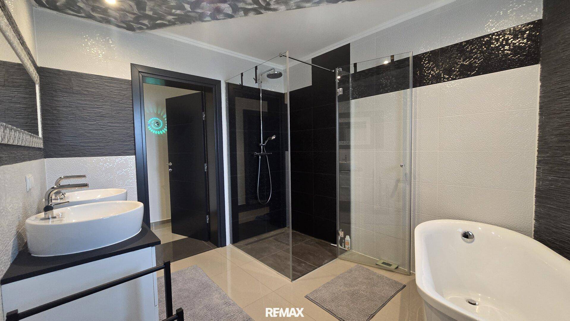 Geräumiges Badezimmer mit freistehender Badewanne, begehbarer Dusche und stilvollen Fliesen.