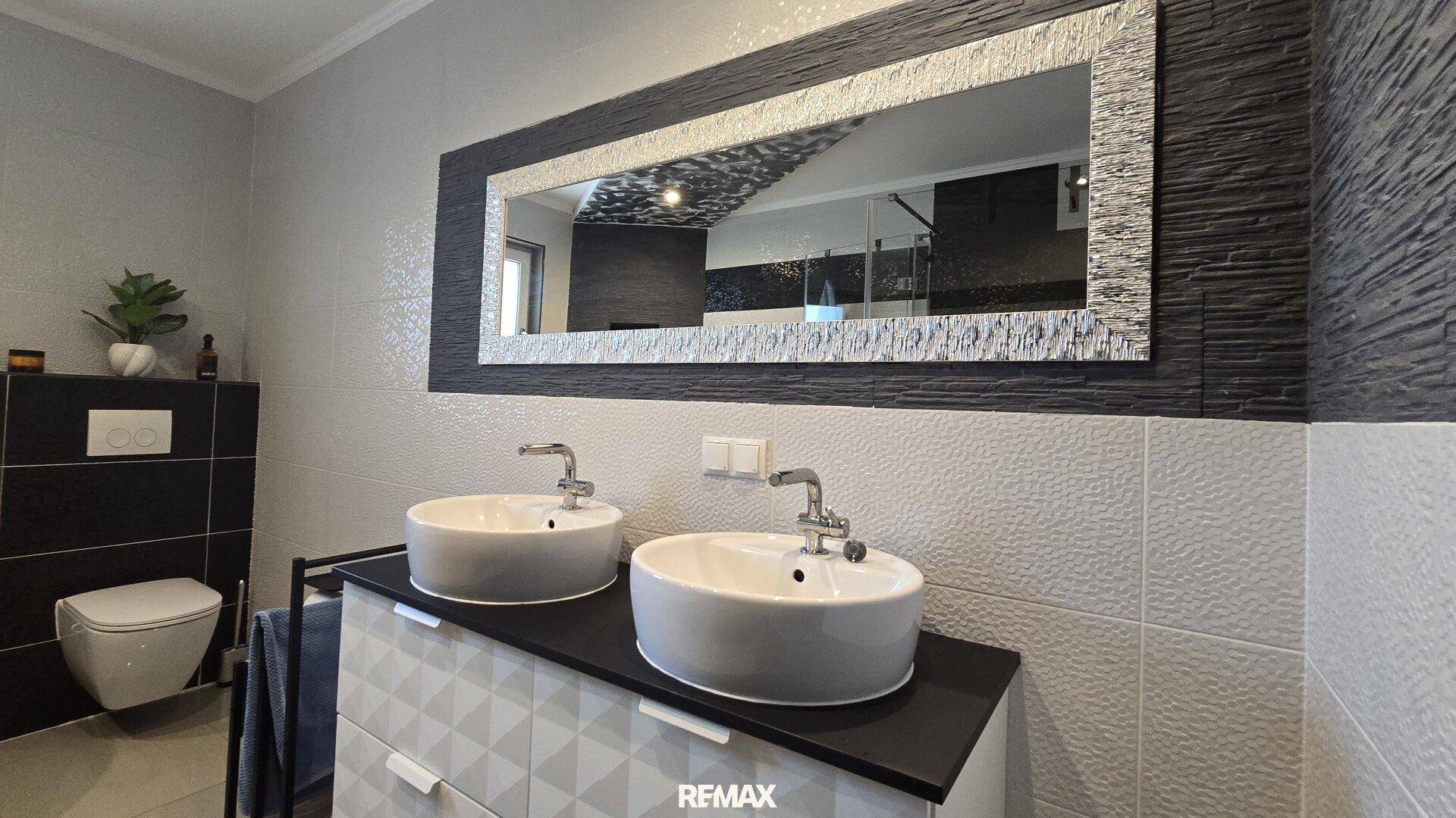 Elegantes Badezimmer mit Doppelwaschbecken, großem Spiegel und modernen Armaturen.