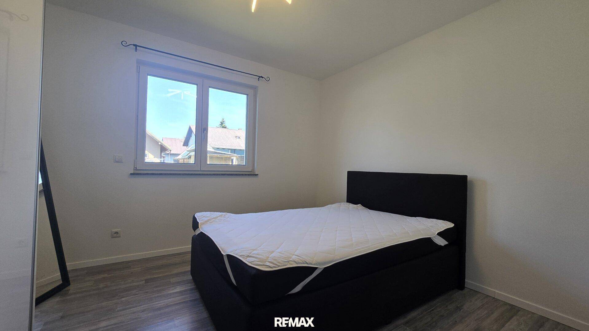 Gemütliches Schlafzimmer mit Doppelbett, modernem Laminatboden und viel Tageslicht.