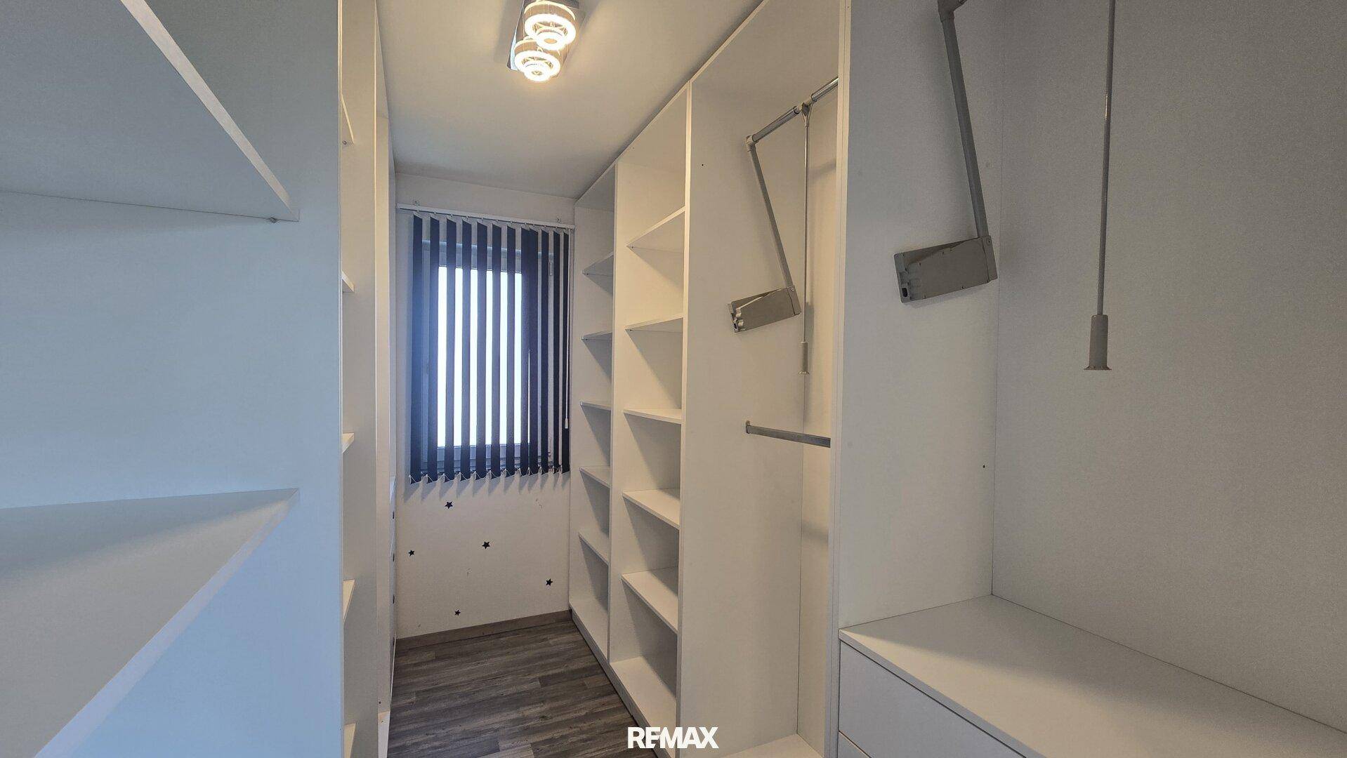 Begehbarer Kleiderschrank mit integrierten Regalen und Aufhängesystemen für Kleidung.