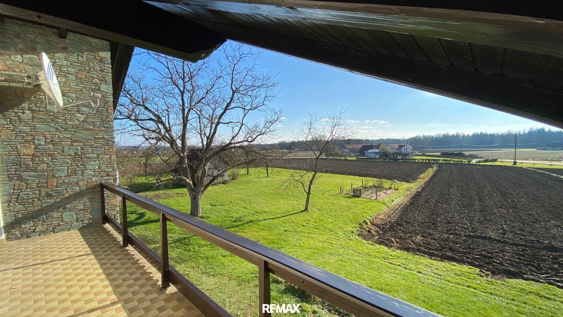 Balkon mit Fliesenboden und weitem Blick über Felder und ländliche Umgebung.