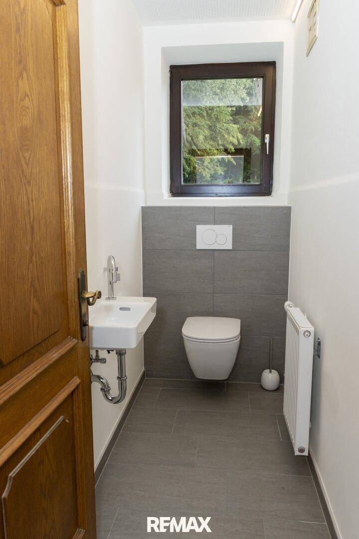 Modernes Gäste-WC mit Wand-WC, kleinem Waschbecken und Fenster.