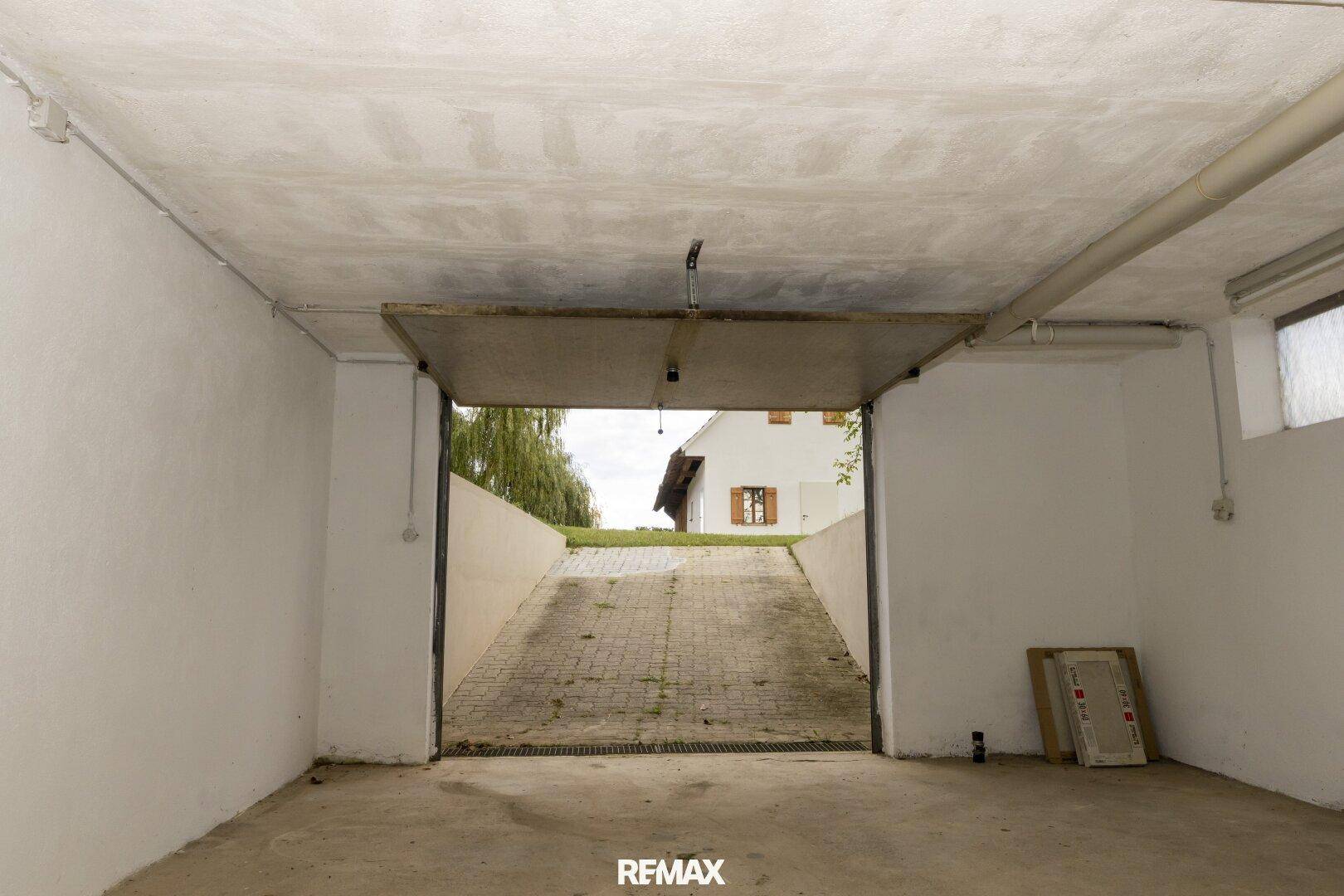 Geräumige Garage mit Betonboden und Zufahrt zum Außenbereich.