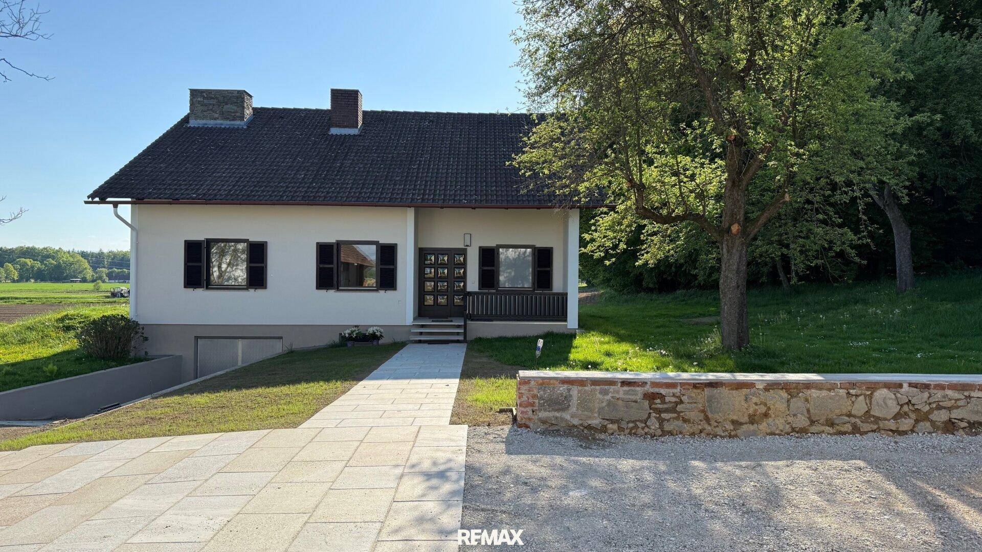 Renoviertes Einfamilienhaus mit neuem Vorplatz und Blick auf die ländliche Umgebung.