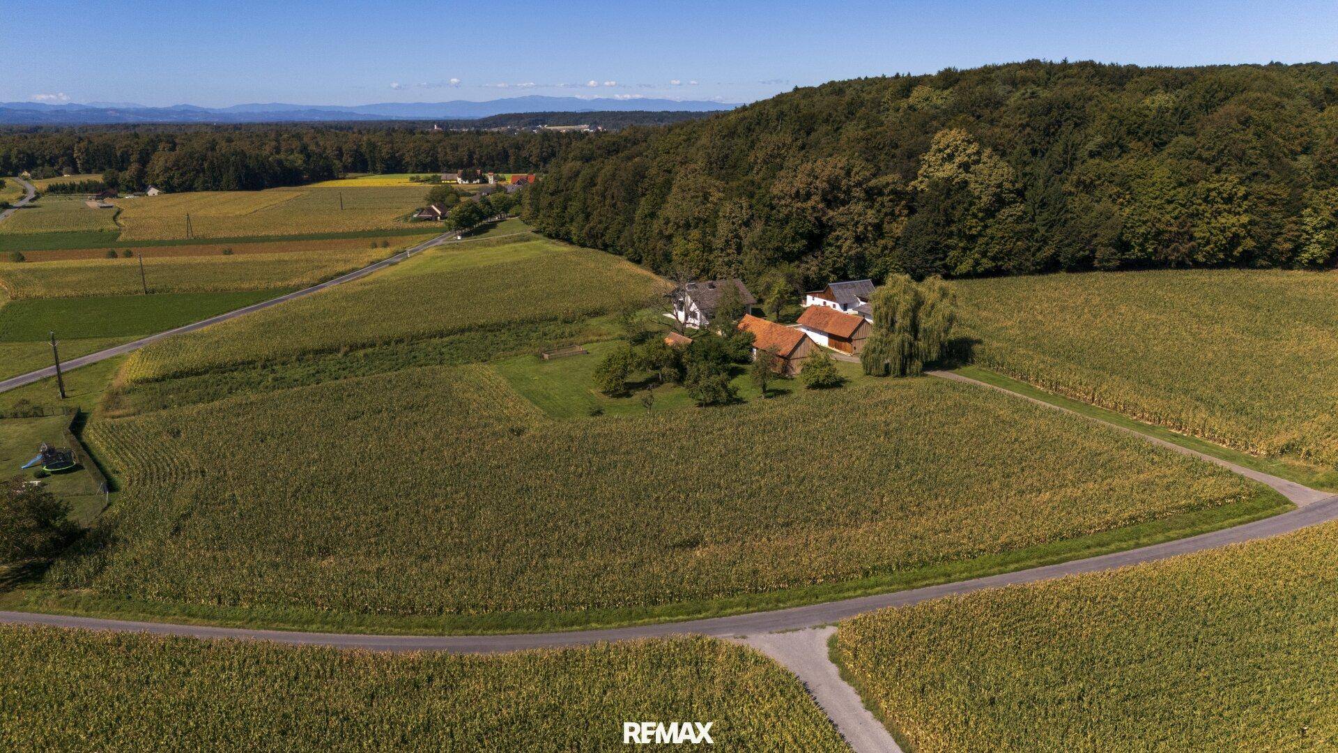 Luftaufnahme eines Anwesens umgeben von weiten Feldern und Wäldern in ländlicher Umgebung.