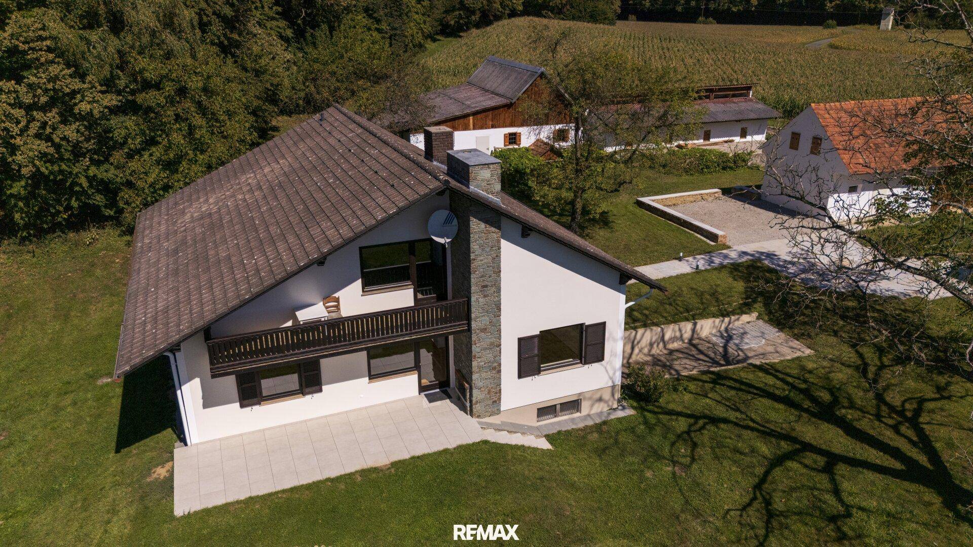 Ansicht des Hauses von oben mit Balkon, Terrasse und umliegender Grünfläche.