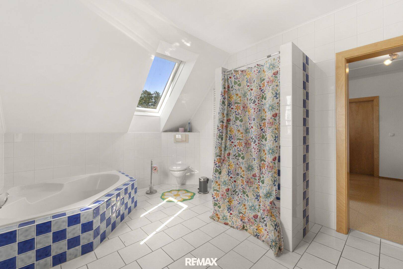 Helles Badezimmer im Dachgeschoss mit Eckbadewanne, Dusche, Toilette und Dachfenster.