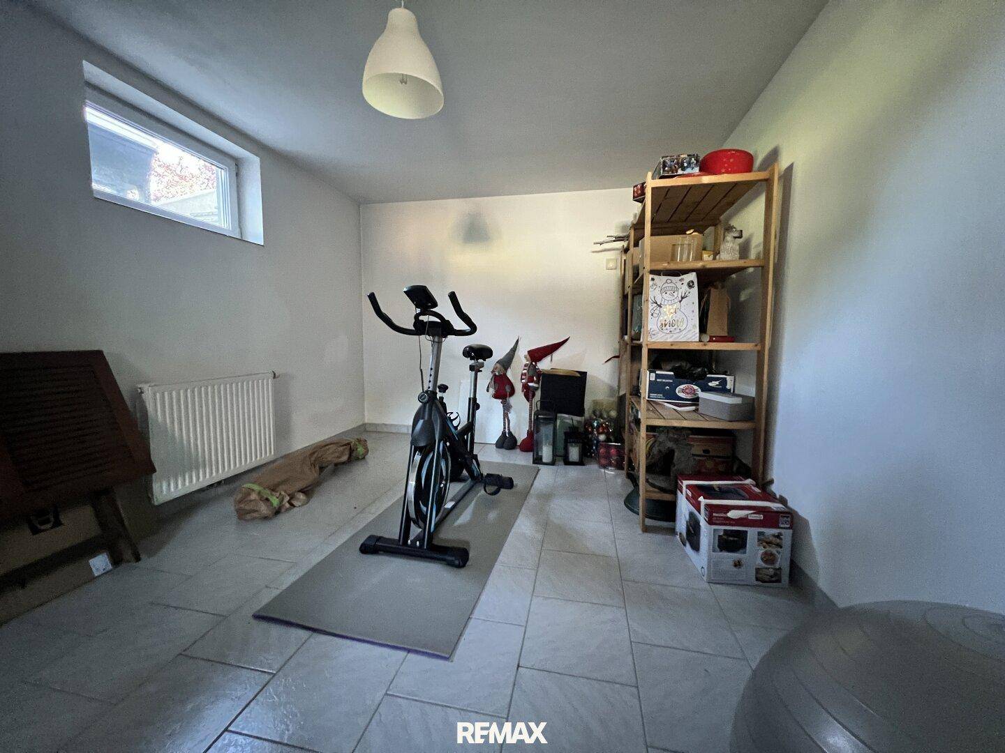 Weiterer Bereich des Fitnessraums im Keller mit Fenster und zusätzlichen Sportgeräten.