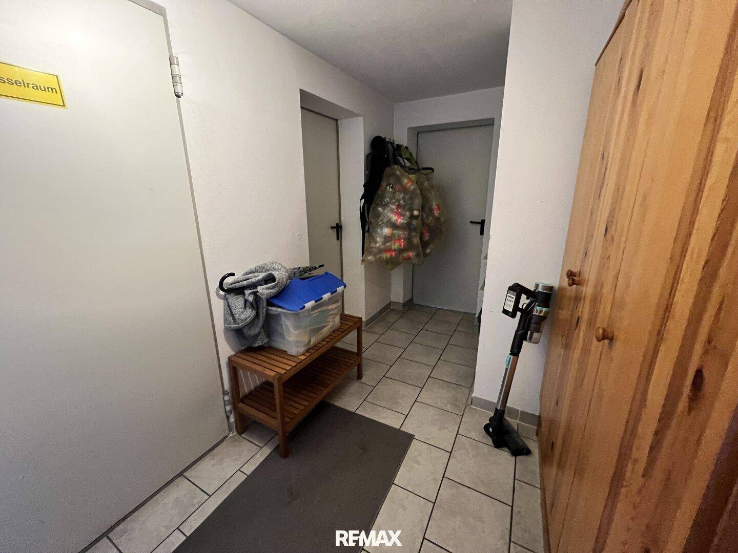 Heller Flur mit Fliesenboden, Holzschrank und Zugang zu weiteren Räumen im Haus.