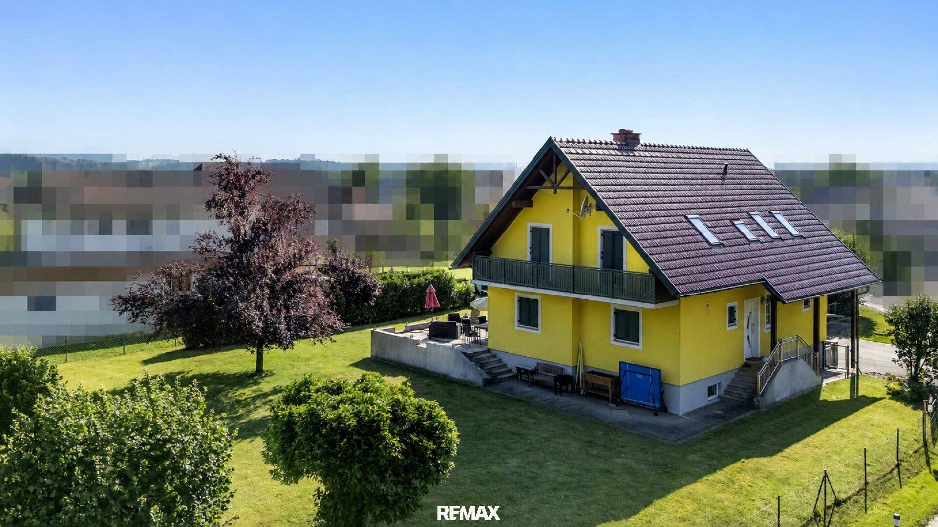 Rückansicht des Hauses mit großer Terrasse, Dachfenstern und Blick auf die Umgebung.