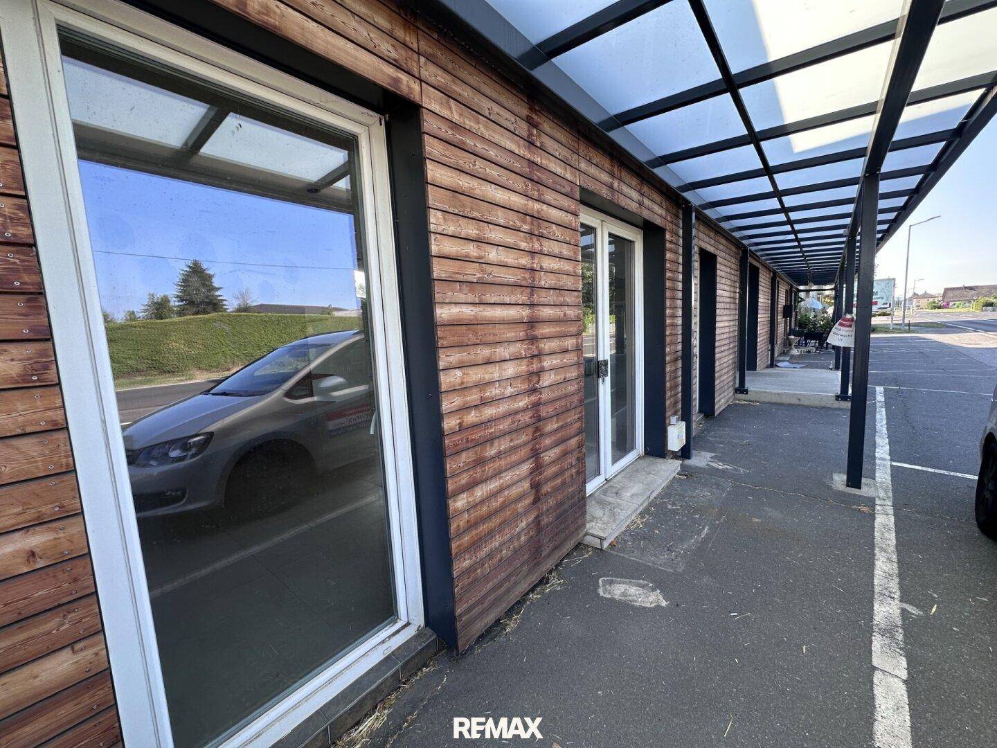 Nahaufnahme der Holzfassade und der Fenster eines Geschäftsgebäudes mit überdachtem Gehweg.