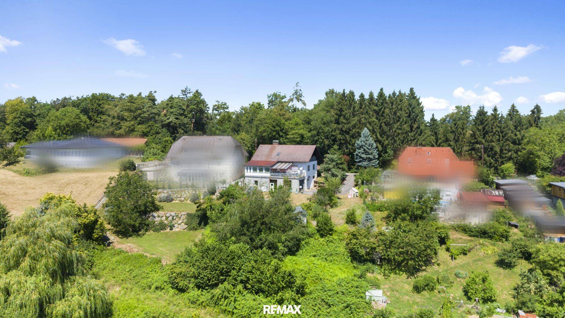 Weitläufige Luftaufnahme eines Hauses mit großem Garten, umgeben von Bäumen und ländlicher Umgebung.