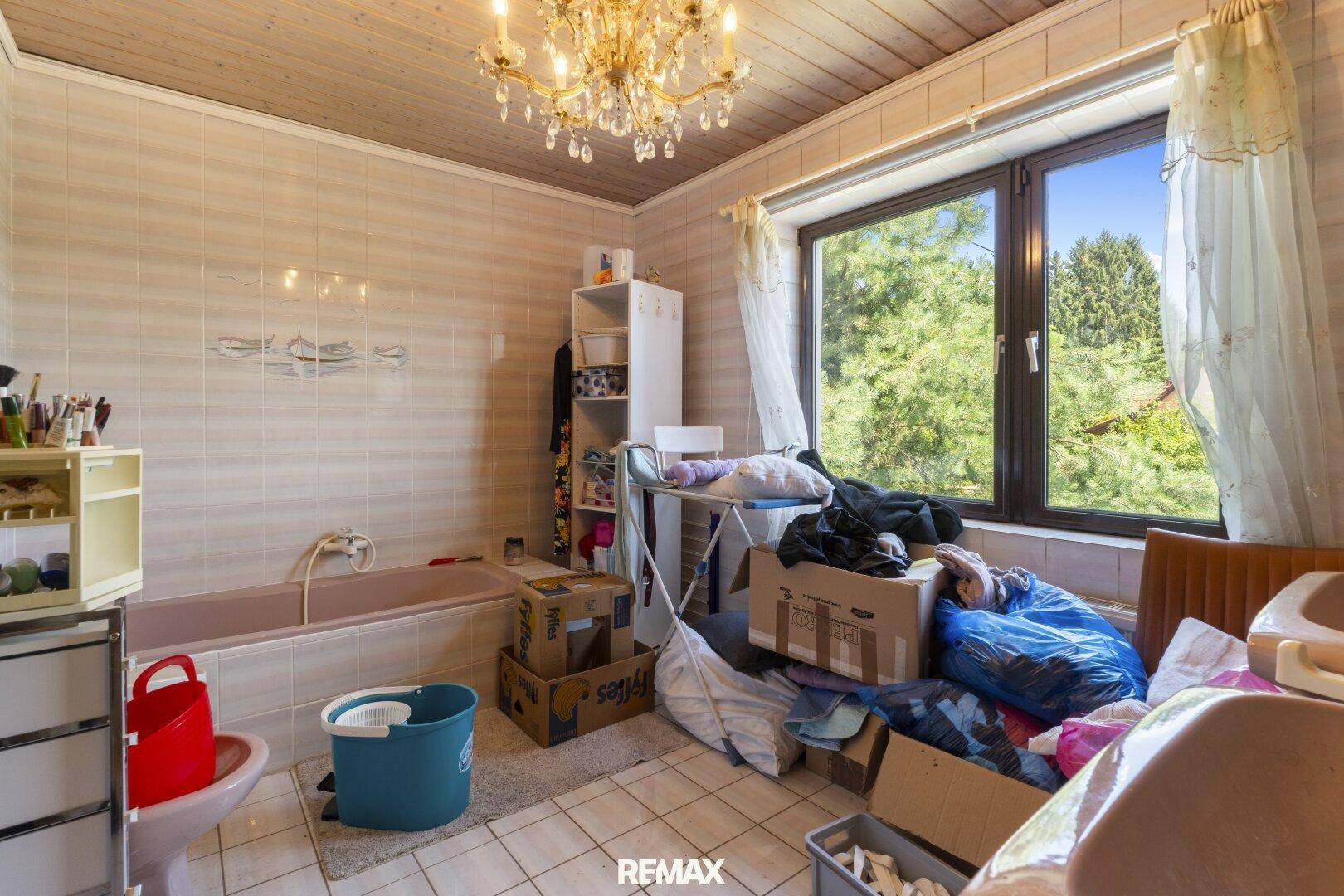 Badezimmer mit rosa Sanitärobjekten, Fliesen an Wänden und Boden sowie einem großen Fenster.