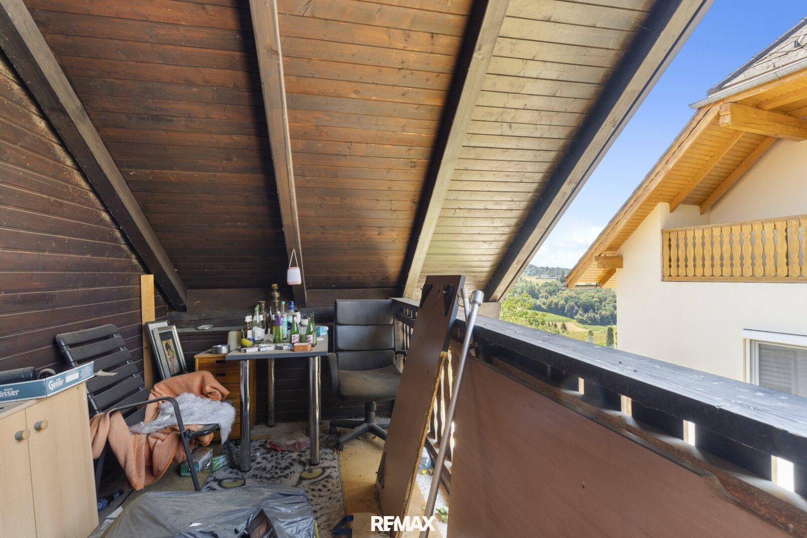 Überdachter Holzbalkon mit weitem Blick über die grüne Landschaft, ideal zum Entspannen.