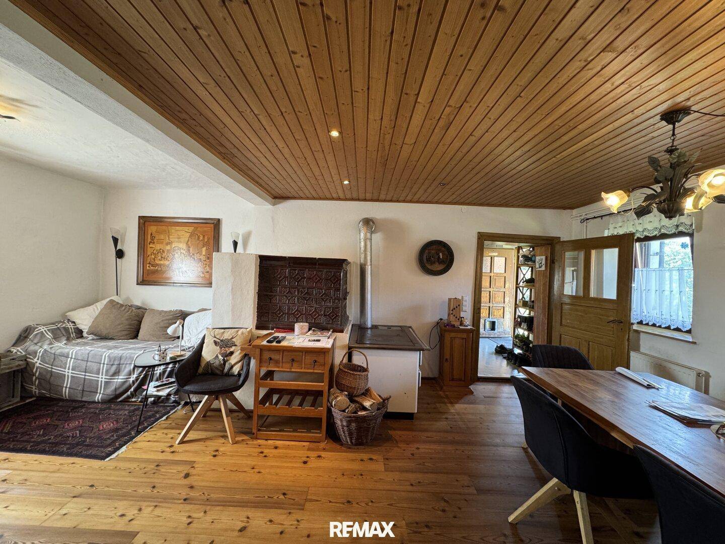 Rustikaler Wohnbereich mit Holzboden, Kachelofen und traditionellen Holzmöbeln, ideal für gesellige Stunden.