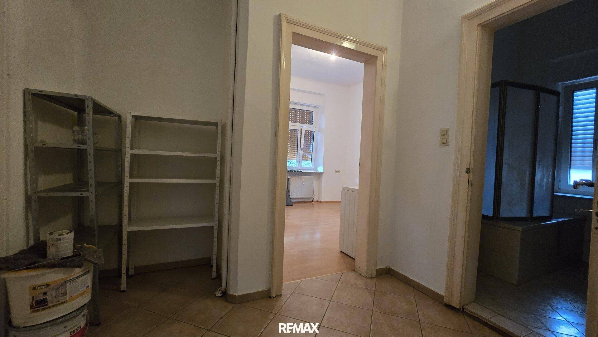 Flur mit praktischen Regalen und Zugang zu weiteren Zimmern, inklusive Badezimmer.
