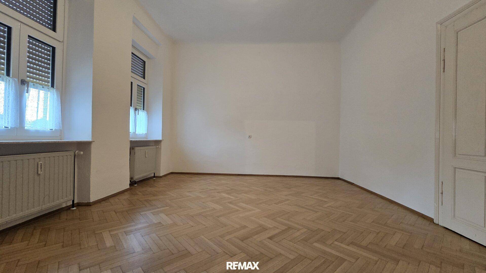 Großes Zimmer mit klassischem Fischgrätparkett und hohen Decken, bereit zur Einrichtung.